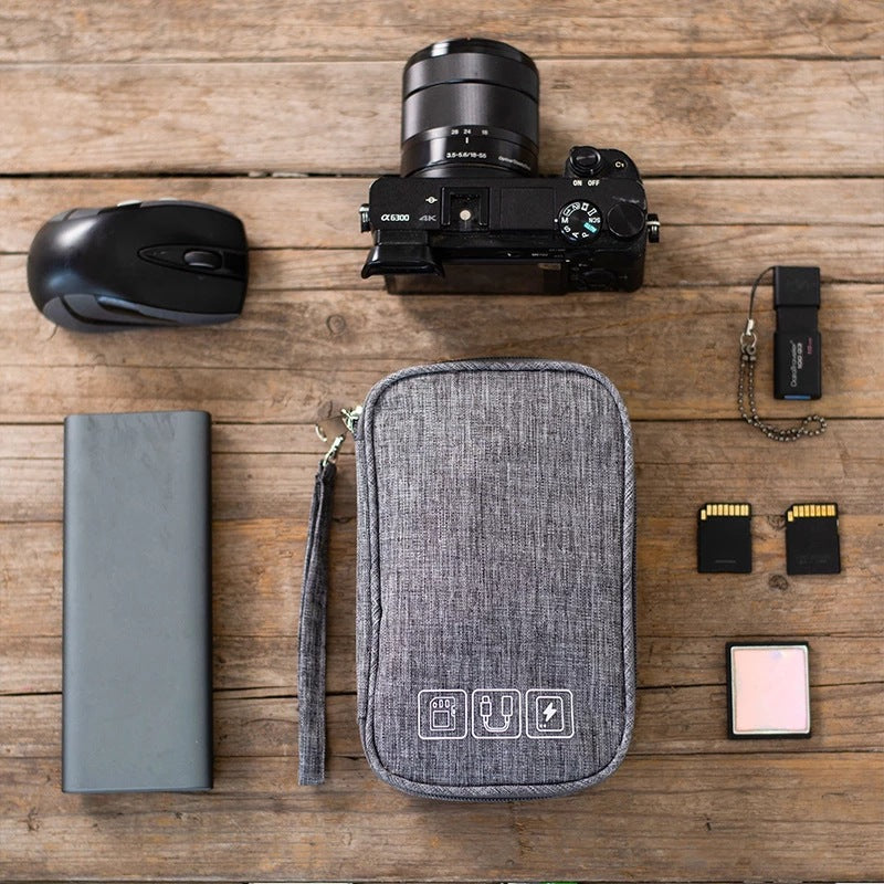 Kabeltasche in Grau neben Kamera, Maus, Speicherkarten und Powerbank
